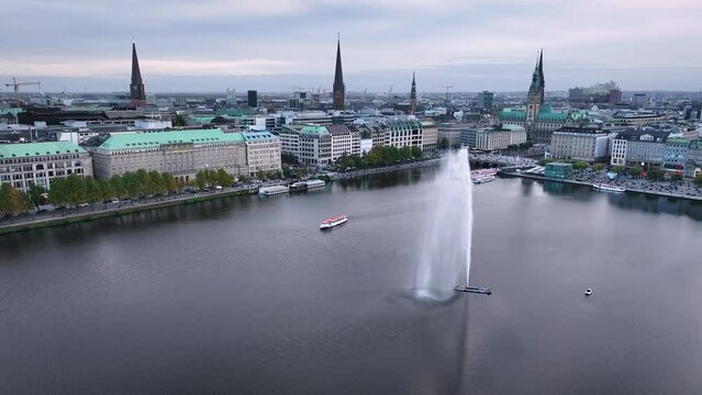 Aerial shot of Alster lake with fountain, where the Alster fountain and steam tourist boat takes center stage  surrounded by the impressive backdrop of the iconic Hamburg skyline.