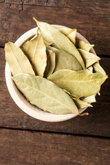 Dried bay leaves in bowl on wooden table. Close up. Top view