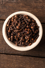 Dried cloves in bowl on wooden table. Close up. Top view