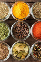 Collection of spices in bowls on wooden background. Top view