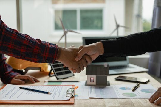 Construction worker and engineer holding hands Real estate concept: architect shaking hands with engineer or builder and successful meeting