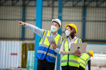 Teamwork engineer in uniform wear protection mask brainstorming workshop industrial factory using laptop and tablet.