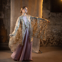A beautiful blonde in a beautiful fantasy sequined dress, a cape or an ethnic robe with wide...