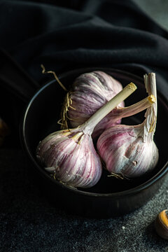 Close-up of fresh garlic bulbs and cloves in a bowl with a napkin