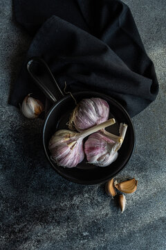 Overhead view of fresh garlic bulbs and cloves in a bowl with a napkin