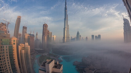Aerial view of Dubai city early morning during fog night to day timelapse.
