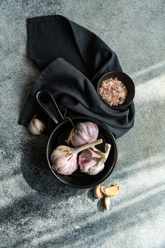 Overhead view of fresh garlic bulbs and cloves in a bowl with a napkin