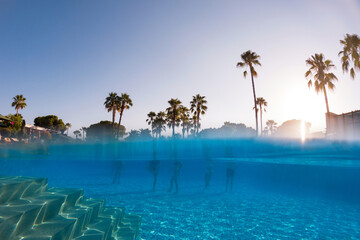 Underwater photography of people standing in pool with copy space. Beach resort vacation by sea....