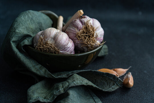 Close-up of fresh garlic bulbs and cloves in a bowl with a napkin