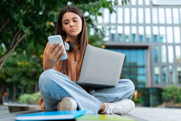 Upset young woman student looking at phone screen, studying online