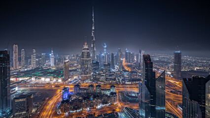 Panorama showing aerial view of tallest towers in Dubai Downtown skyline and highway night...