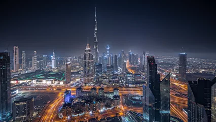 Rolgordijnen Panorama showing aerial view of tallest towers in Dubai Downtown skyline and highway night timelapse. © neiezhmakov