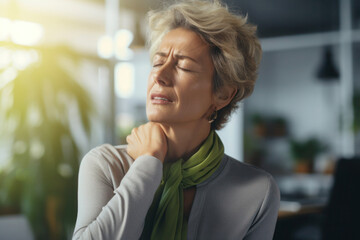 Senior overworked woman suffering from neck pain at the office - obrazy, fototapety, plakaty