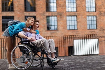 Hansome gen Z boy in a wheelchair with his girlfriends. Love with disability. Inclusion, equality,...