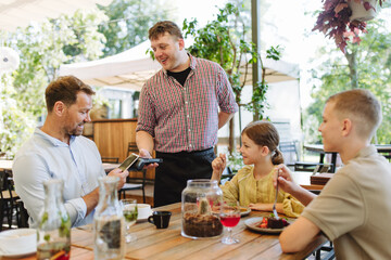 Father and children ordering food from waiter. Single-parent family having dinner at restaurant. Concept of Father's Day.