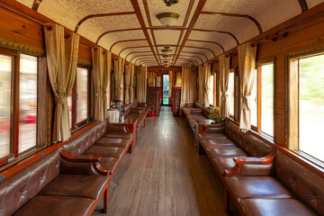 Interior of vintage old train carriage with leather chair, wooden floor, yellow curtains in Da Lat...