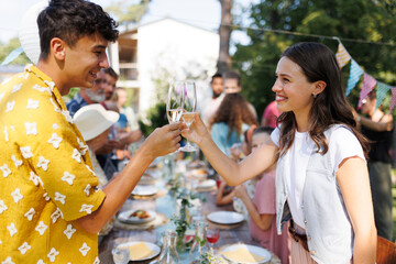Friends clinking glasses at summer garden party. Celebratory toast at the table.