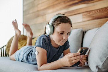 Diabetic girl watching social media content on smart phone.The CGM device makes life of schoolgirl. easier, helping manage illness and focus on other activities.