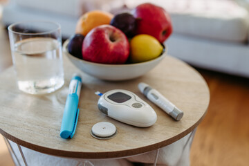 Close up of diabetes supplies and devices on table. Continuous glucose monitor, insulin pen, blood...