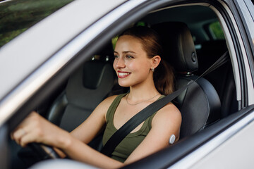 Fototapeta na wymiar Woman with continuous glucose monitor driving car. Diabetic woman with CGM needs to raise her blood sugar level to continue driving.