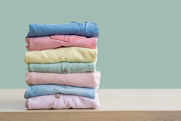 Stack of clean freshly laundered, neatly folded women's clothes on wooden table