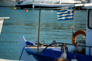 Imbarcazione piccola ormeggiata al porto con bandiera greca che sventola
