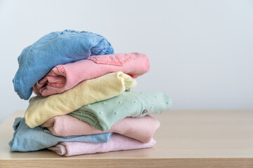 Stack of clean freshly laundered, neatly folded women's clothes on wooden table