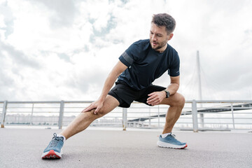 Runner man smiles exercise stretching leg muscles active lifestyle. Mental health and motivation...