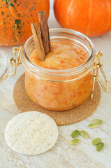 Homemade pumpkin face mask in a glass jar and loofah sponge. Natural autumn beauty treatment and spa recipe.