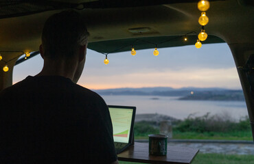 Man working remotely from his camper van on the sea coast