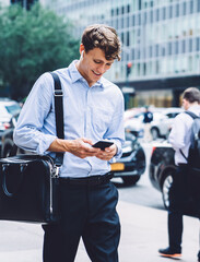 Male worker texting on phone walking down street