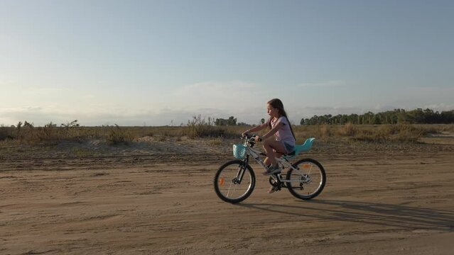 Young girl on her bicycle making her way home on a dry desert road. Gimbal