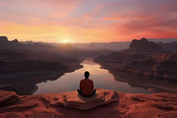 Foto op Canvas hombre sentado meditando en posición de yoga sobre piedra en la cima de una montaña al  atardecer sobre rio y montañas © Helena GARCIA