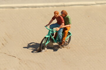 Two figures ride a bicycle to the square