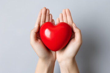 Obraz premium Two hands tenderly holding a vibrant red heart, symbolizing the profound and compassionate connection between individuals in a simple yet powerful gesture of love and care. Ai generated