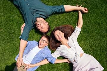 Cute family lies hugging on the front lawn