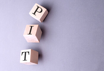 Word PIT on wooden block on the grey background