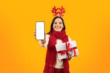 Lady Showing Phone Screen Holding Xmas Gift Box, Yellow Background