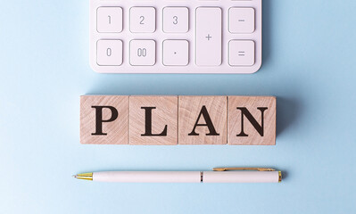 PLAN on wooden cubes with pen and calculator, financial concept