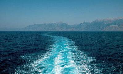 Boat white wake prop wash foam on blue sea background texture. Ripple water spray behind ship. Space