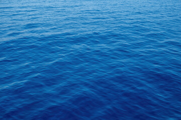 Obraz premium Rippled empty sea background texture, close up view. Wavy blue ocean water, ad template, copy space