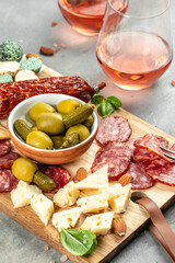 antipasti wine snacks set. Cutting board with salami, cheese, olives and rose wine. vertical image. top view