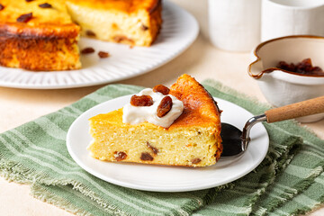 A piece of homemade cottage cheese casserole pie with raisins and .sour cream. Baked cheesecake made with dairy products, eggs, semolina flour and vanilla. Green napkin.