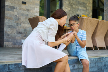 Woman blows on the wound on her sons knee