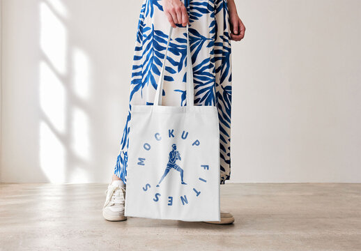 Mockup of woman holding customizable tote bag, low section