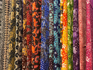 Colourful batik cloth hanging neatly on the display of a boutique - obrazy, fototapety, plakaty