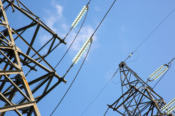 High voltage tower with electrical voltage wires isolates close-up against the background of clouds. Energy industry.