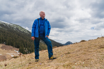 Man hiker enjoys snowdrops blooming at Carpathian mountains