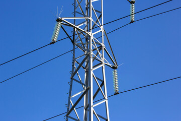 Electrical tower with voltage transmission wires against the background of blue sky. High voltage tower. power line support with wires for electricity transmission. Energy industry.