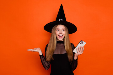 Photo of impressed excited girl dressed dark witch dress headwear texting apple samsung iphone...
